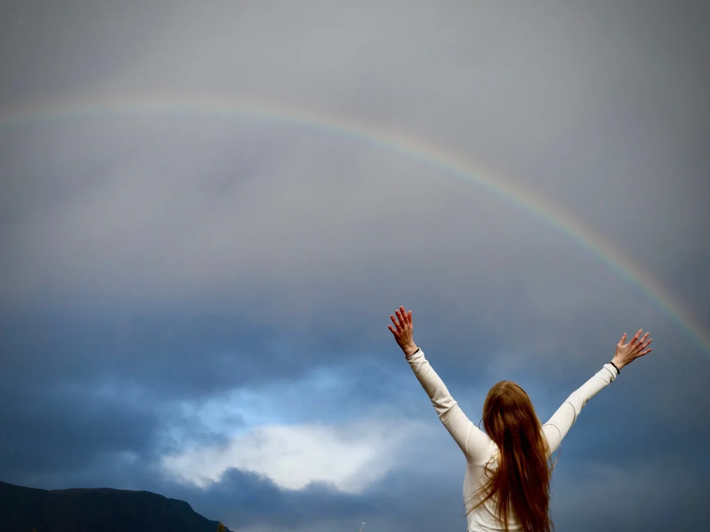 Woman reaching out to a rainbow.